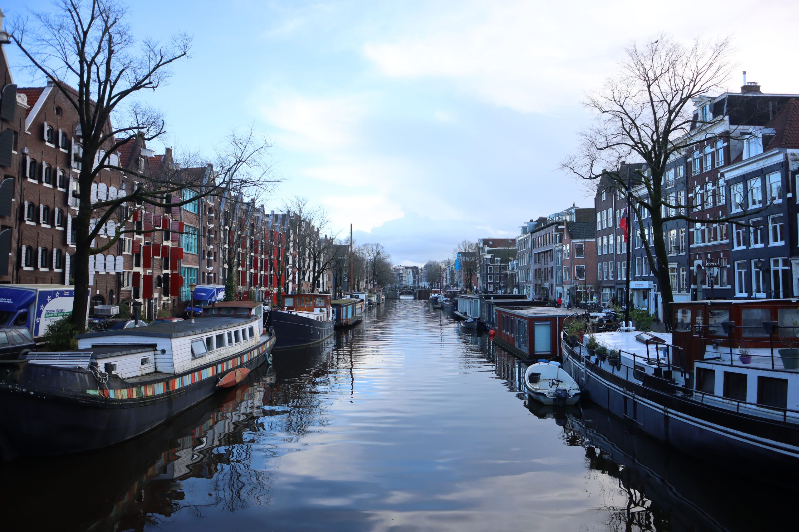 View of a canal with boats and buildings on both sides under a cloudy sky.